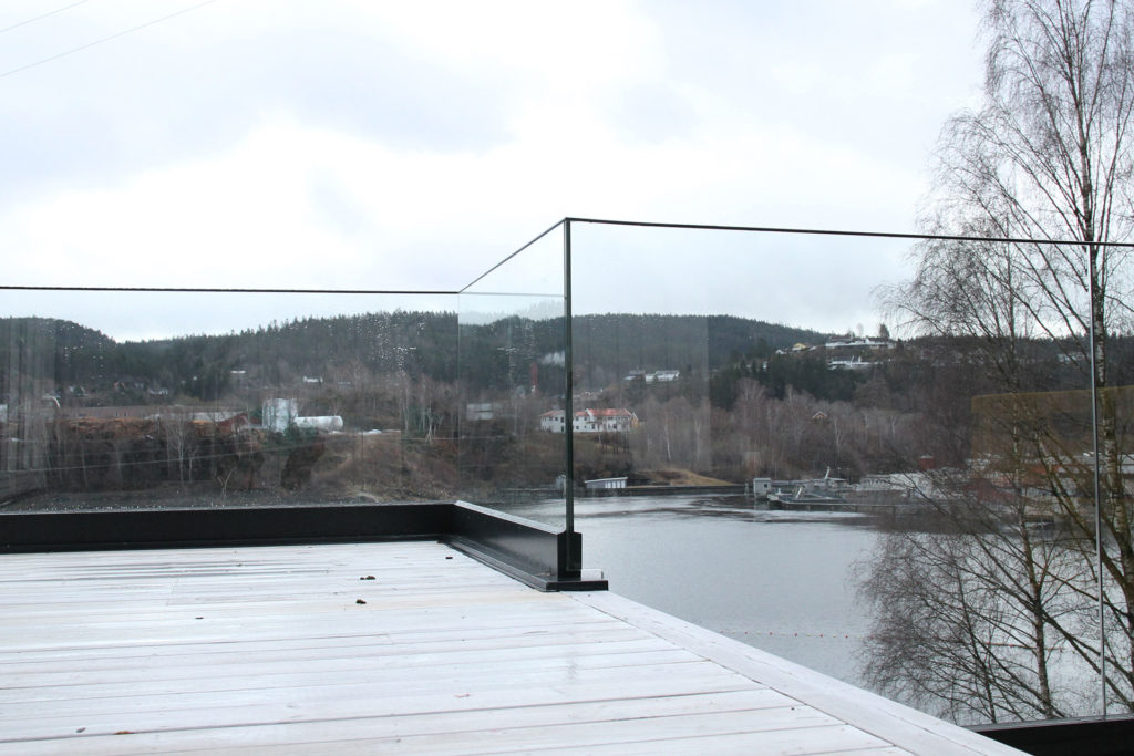 Glassrekkverk på terrasse med utsikt i bakgrunnen